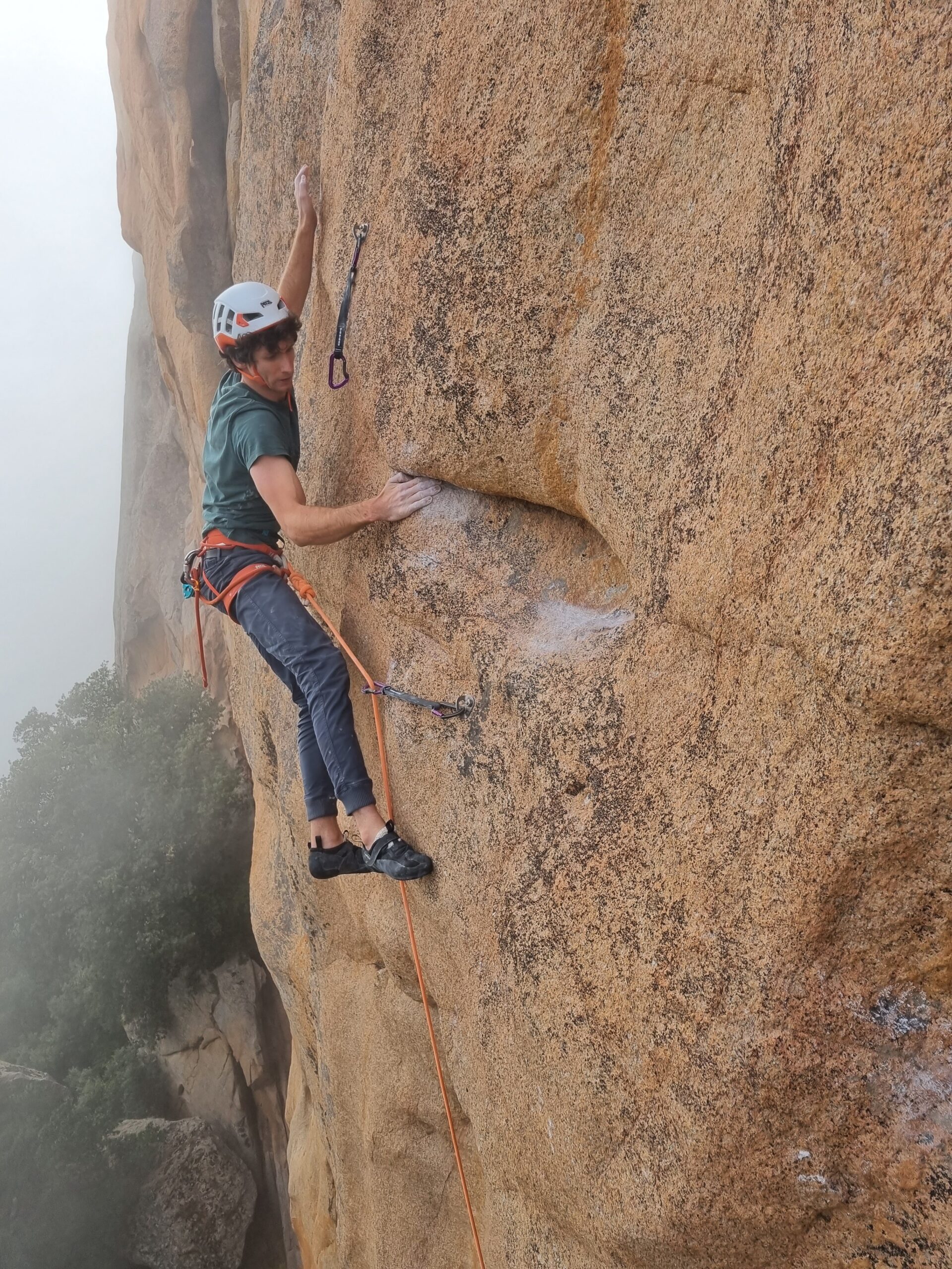 A climber sport climbing on granite rock you can see the bolts in the rock and the quickdraws clipped into the bolts and his rope. Trad vs sport climbing what are the differences?