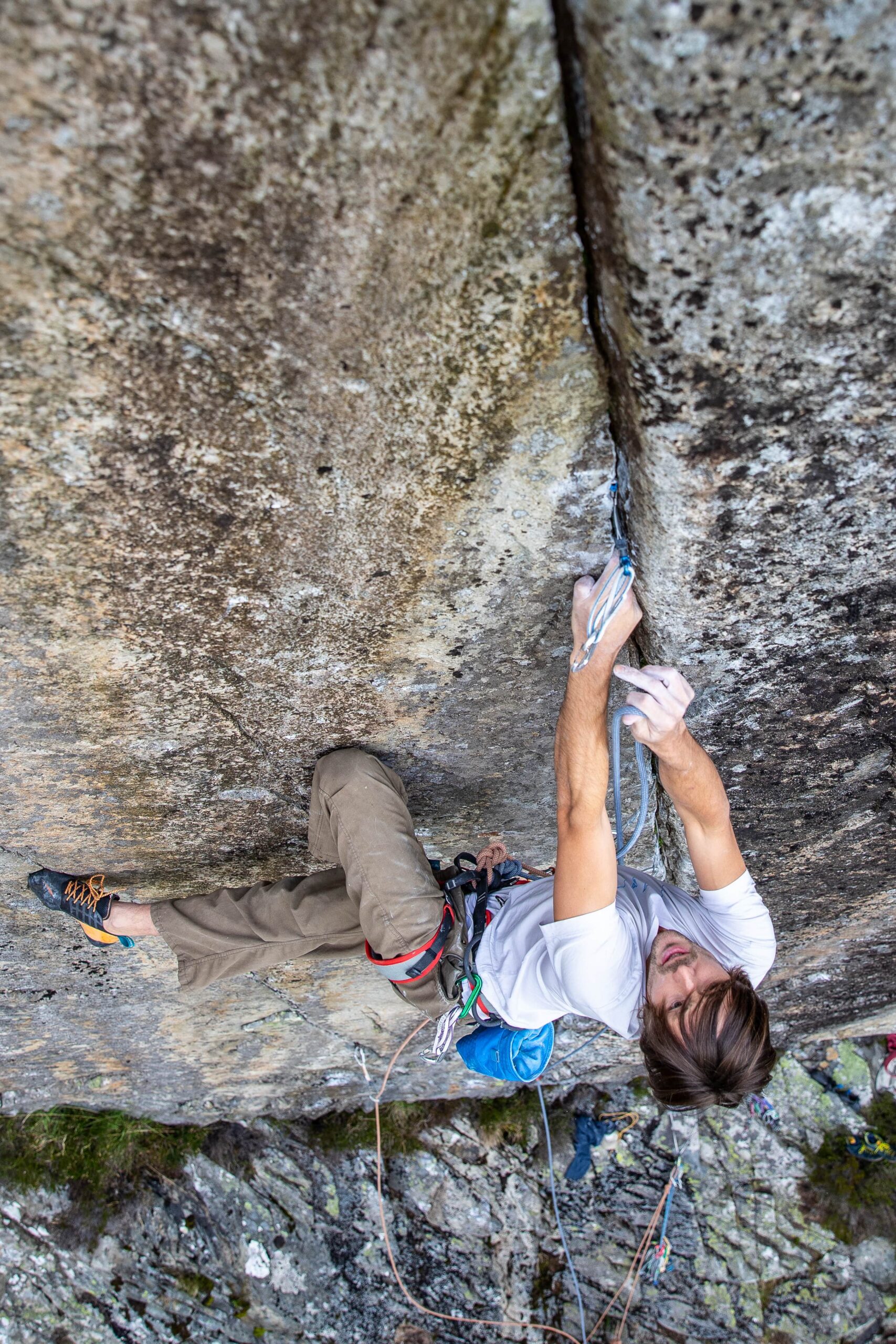 A climber trad climbing with a cam visible above his head. Trad vs sport climbing what are the differences?
