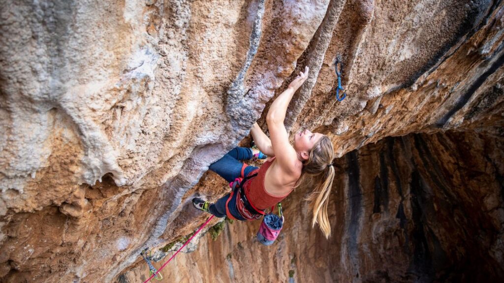 Climber reaching for a hold on an overhanging cave route