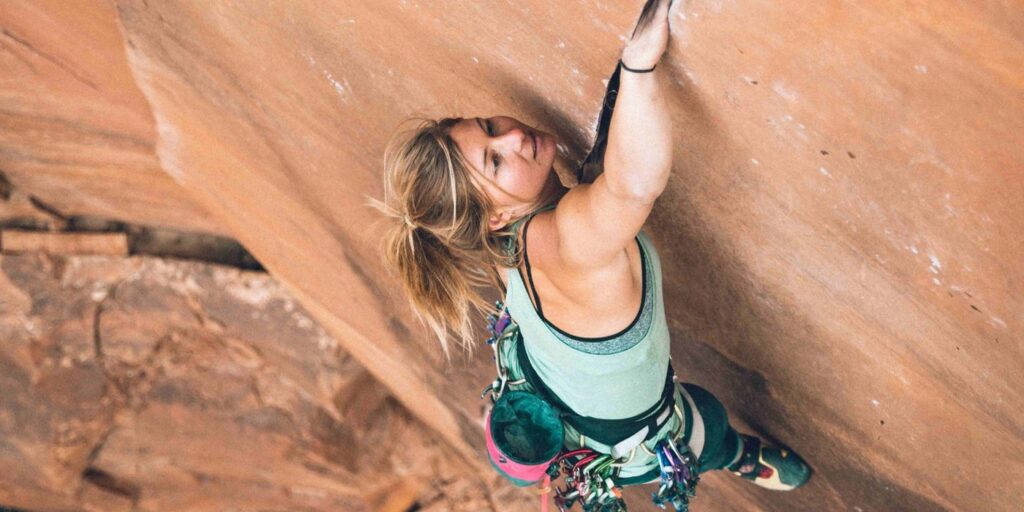 Climber on a sandstone crack, fully racked with trad gear