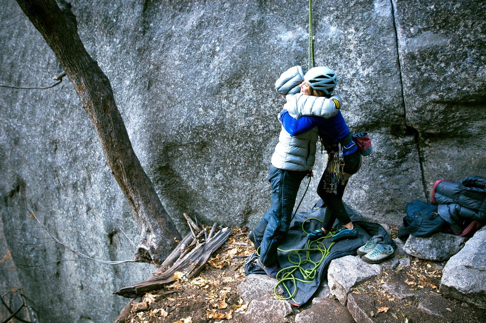 Two climbers embracing at an outdoor crag