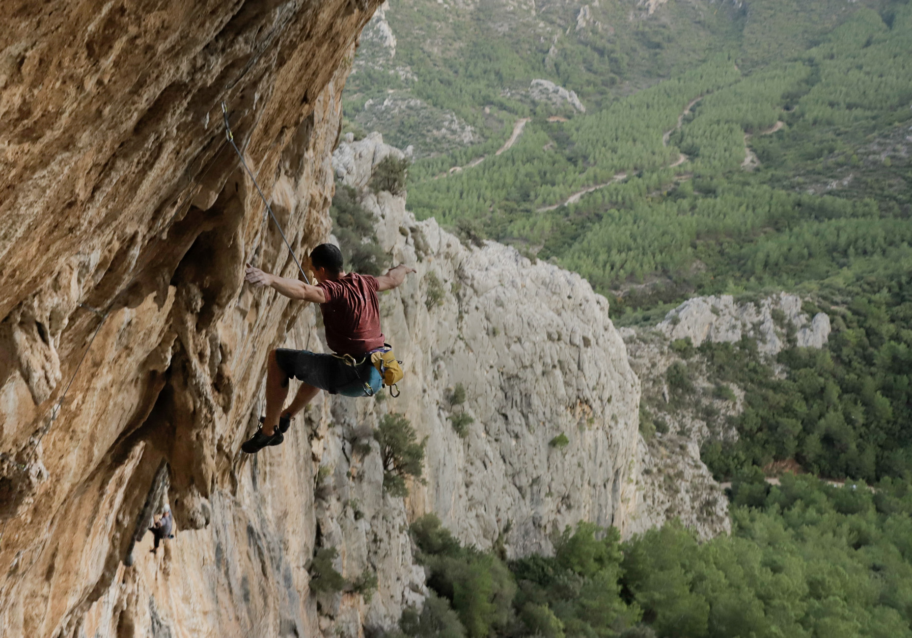 Climber reaching for a hold on an overhanging rock face