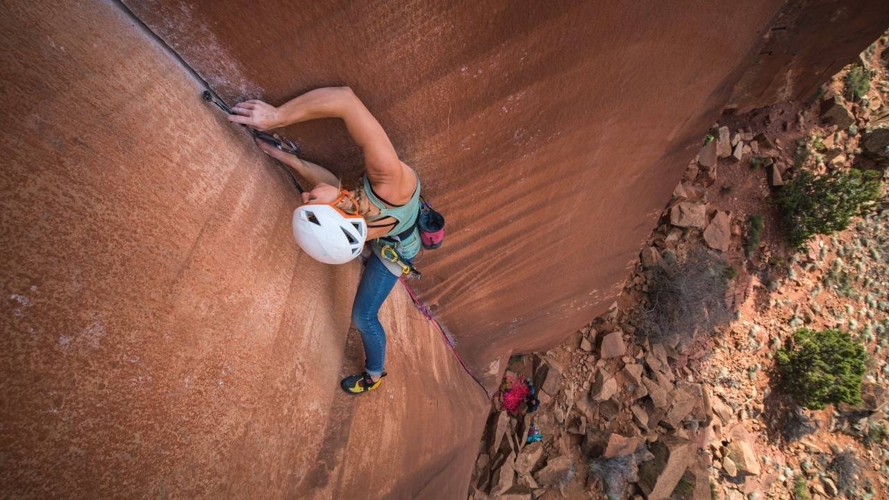 Climber reaching for a hold on an overhanging rock face